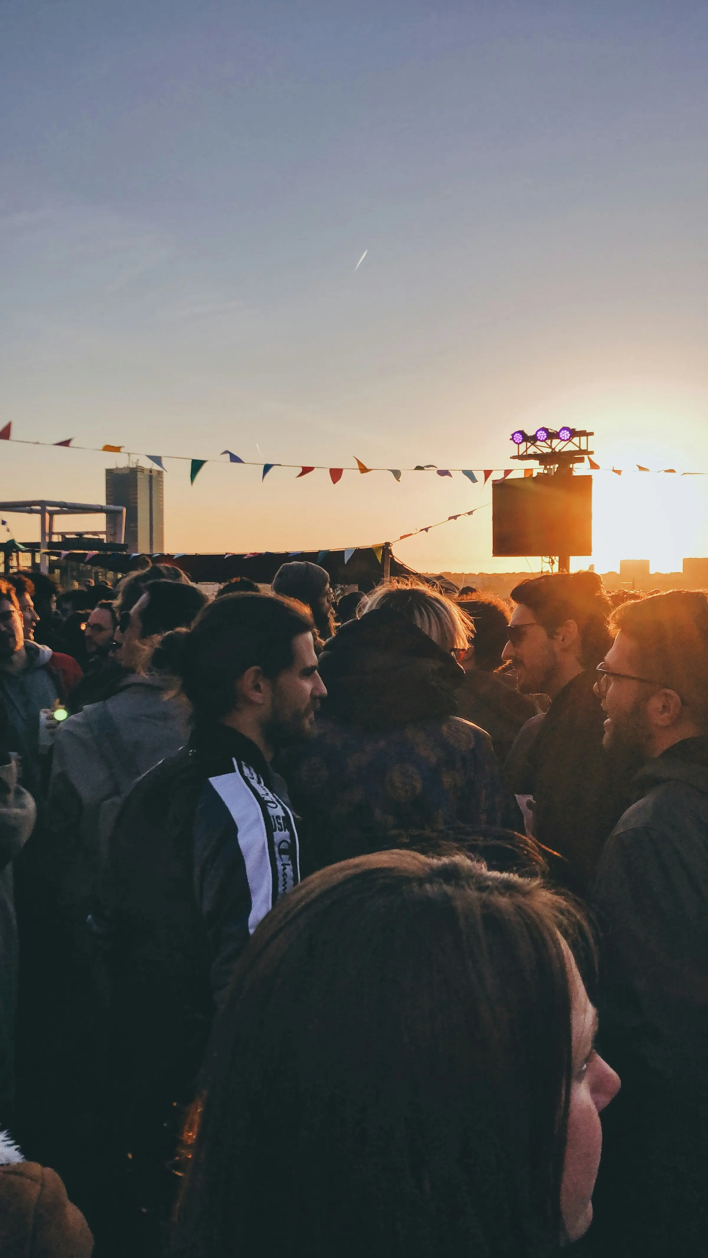 A crowd gathered at golden hour under festival bunting