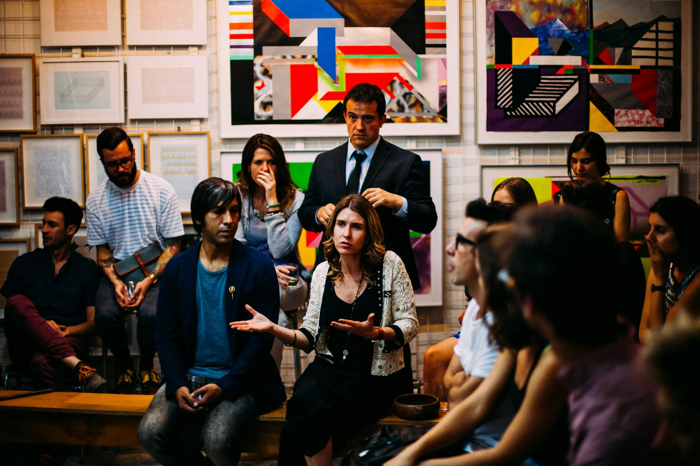 A mixed group of people sitting close together in discussion, one woman speaking