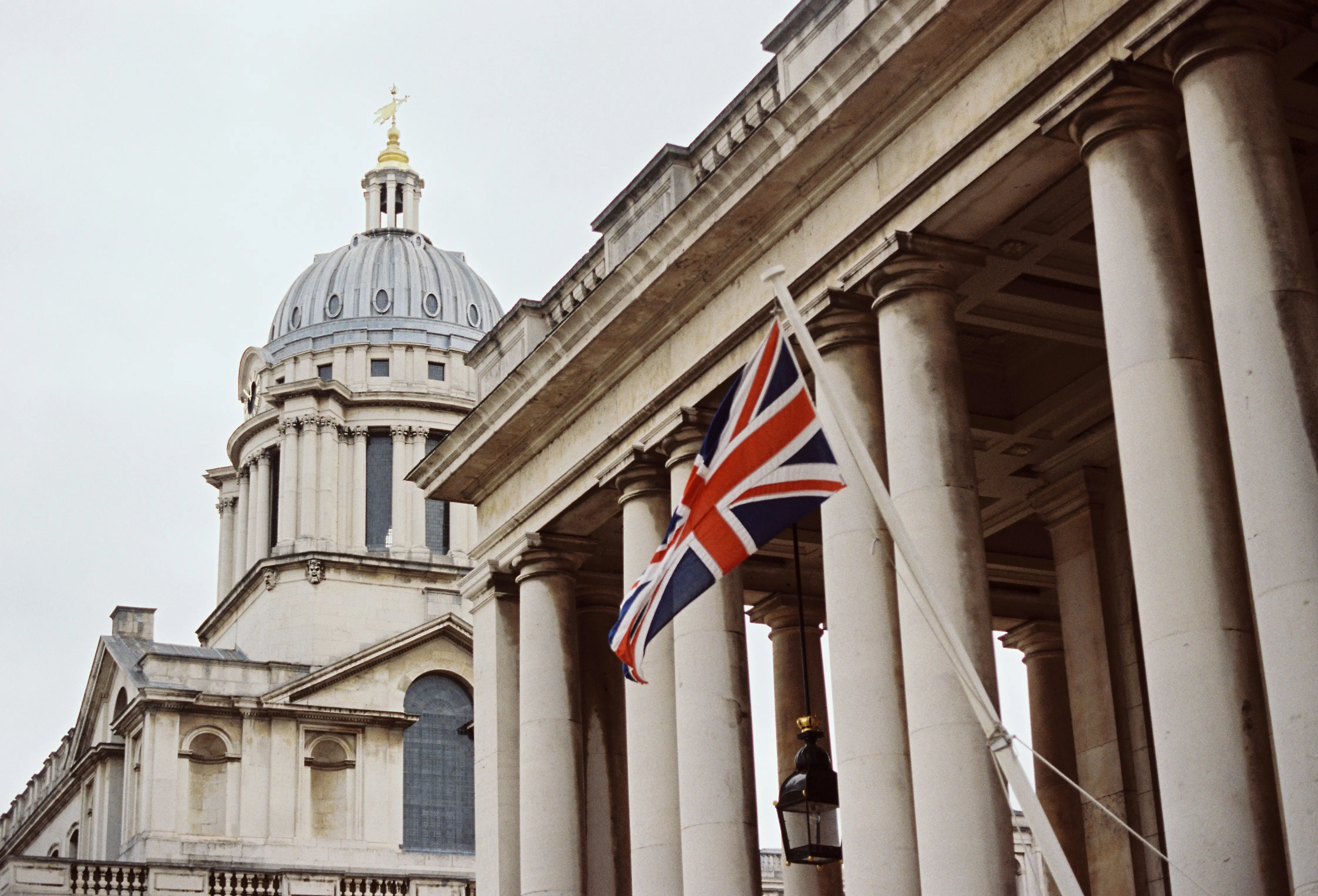 A Union Jack hanging from the stone colonnades of the Old Royal Naval College, Greenwich